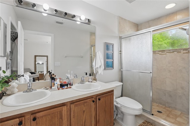 bathroom with double vanity, a stall shower, toilet, and a sink