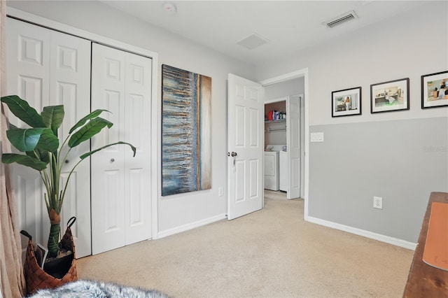 bedroom featuring visible vents, baseboards, light colored carpet, a closet, and washer and dryer