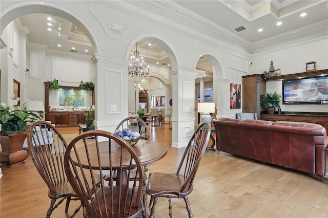 dining space with a decorative wall, decorative columns, light wood-style flooring, and ornamental molding