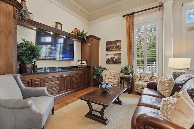 living area featuring light wood-style floors, ornamental molding, and ornate columns