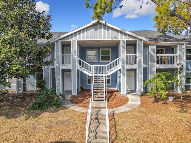 view of front of property with stairway, covered porch, board and batten siding, and roof with shingles