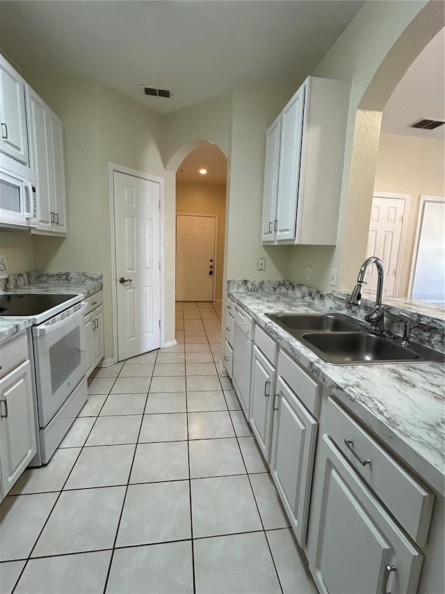 kitchen with a sink, visible vents, white appliances, and light tile patterned floors