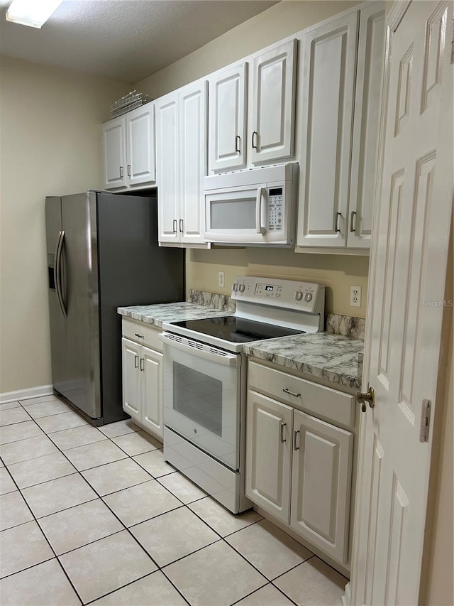 kitchen featuring light stone counters, white appliances, light tile patterned flooring, and white cabinetry