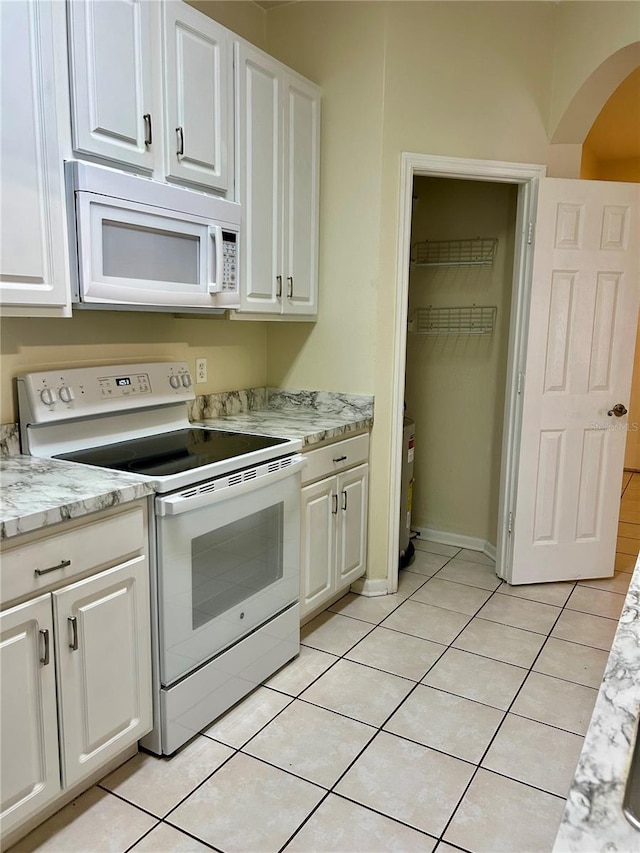 kitchen featuring white appliances, white cabinets, light tile patterned flooring, and arched walkways