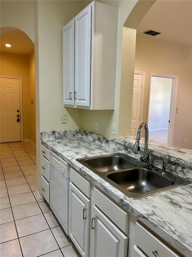 kitchen with white cabinetry, light tile patterned flooring, arched walkways, a sink, and dishwasher