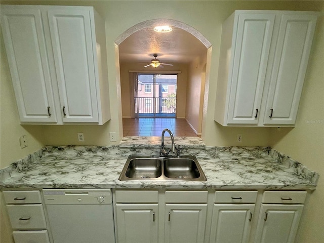 kitchen with arched walkways, dishwasher, light countertops, and a sink