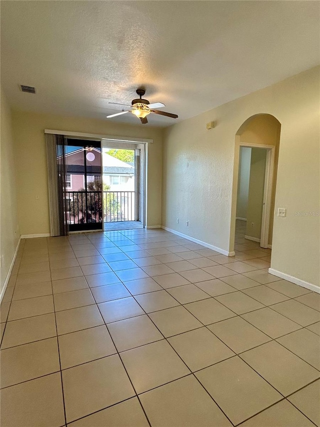 unfurnished room with light tile patterned floors, a ceiling fan, visible vents, arched walkways, and a textured ceiling