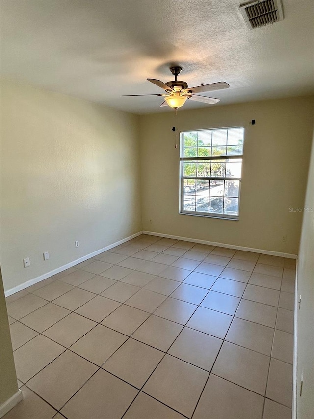 unfurnished room with baseboards, visible vents, light tile patterned flooring, ceiling fan, and a textured ceiling