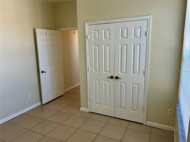 unfurnished bedroom with light tile patterned floors, baseboards, and a closet