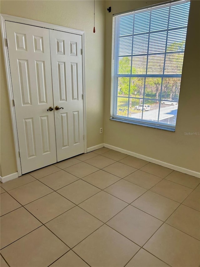 unfurnished bedroom featuring light tile patterned floors, a closet, and baseboards