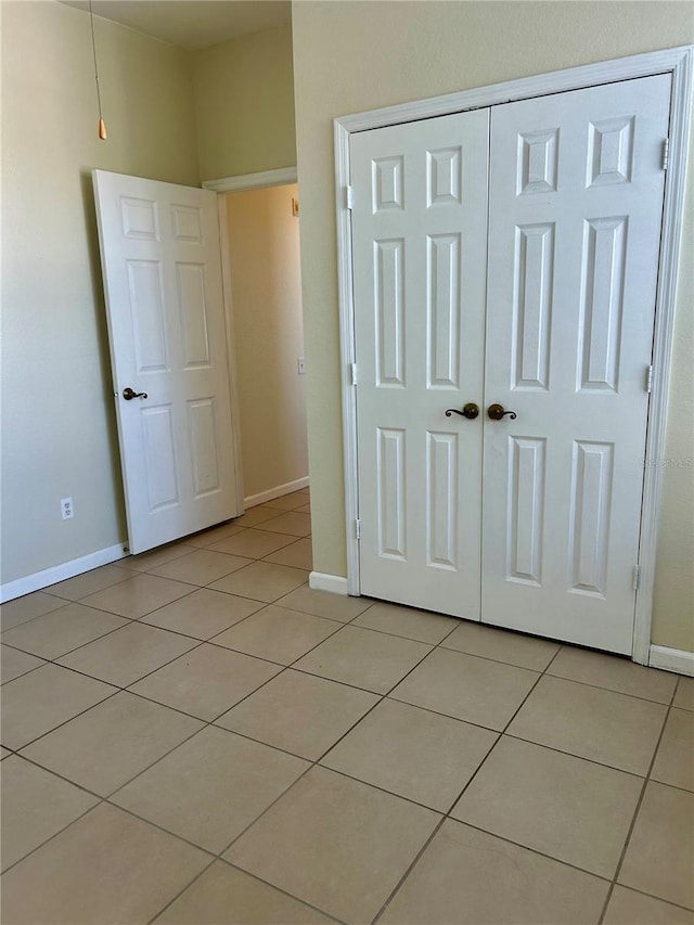 unfurnished bedroom with light tile patterned floors, baseboards, and a closet