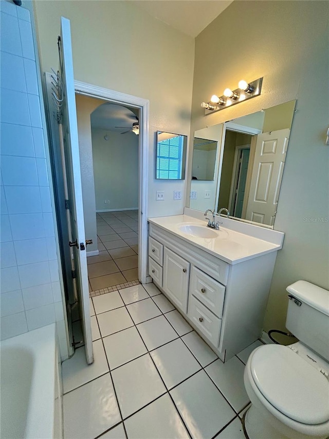 bathroom with tile patterned flooring, a washtub, toilet, vanity, and a ceiling fan