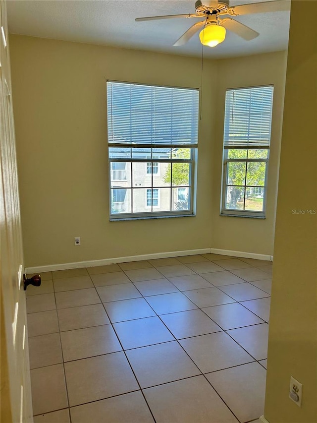 empty room with light tile patterned floors, baseboards, and ceiling fan