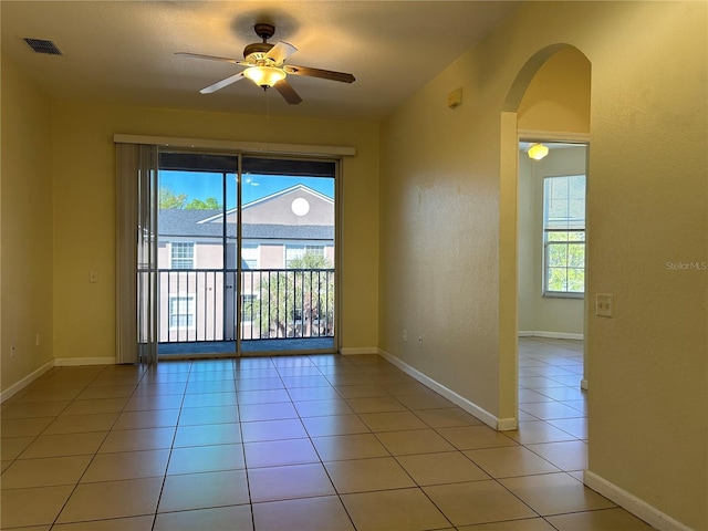 empty room with a ceiling fan, plenty of natural light, arched walkways, and visible vents