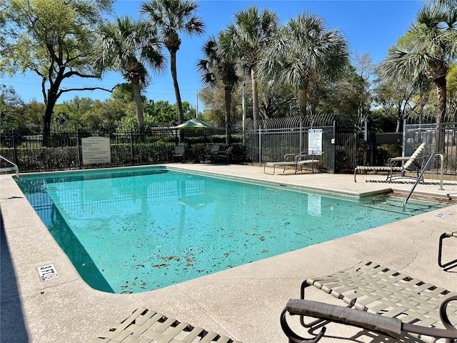 community pool with a patio and fence