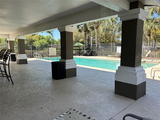 pool featuring fence and a patio area