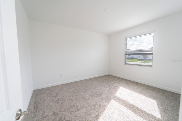 spare room featuring carpet and baseboards