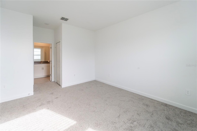 spare room featuring light carpet, visible vents, and baseboards