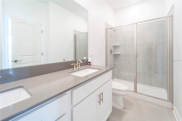 full bathroom featuring double vanity, a sink, tile patterned flooring, a shower stall, and toilet