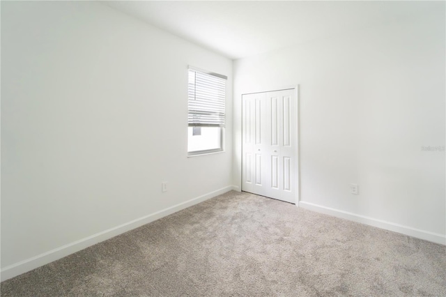 spare room featuring baseboards and light colored carpet