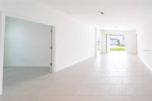 empty room featuring light tile patterned floors, visible vents, and baseboards