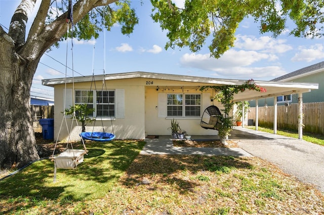 view of front facade with an attached carport, fence, a front lawn, and driveway