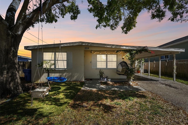 view of front of home with a carport, fence, a front lawn, and driveway