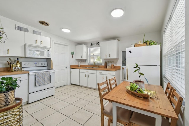 kitchen with white appliances, visible vents, light tile patterned flooring, a sink, and white cabinetry