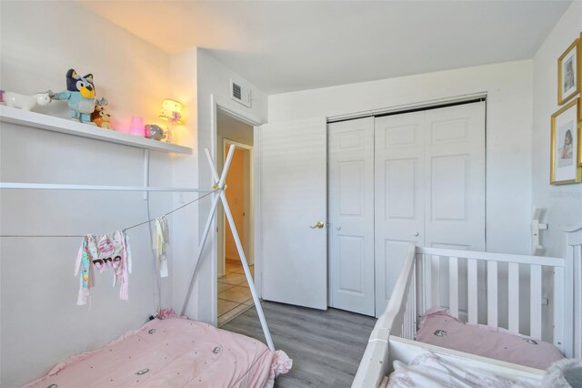 bedroom with a closet, visible vents, and wood finished floors