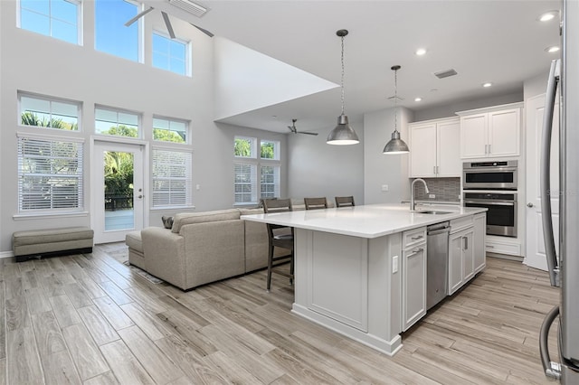 kitchen with light wood finished floors, open floor plan, visible vents, and a sink