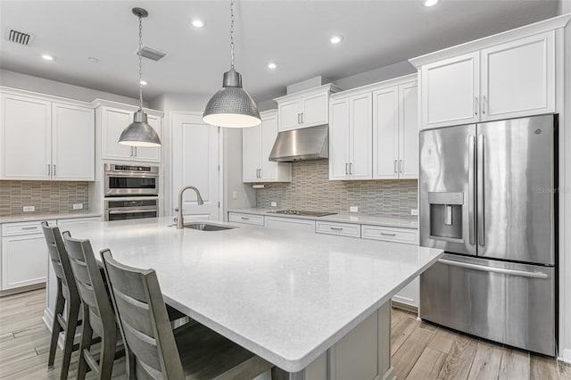 kitchen with visible vents, light wood-style flooring, a sink, under cabinet range hood, and appliances with stainless steel finishes