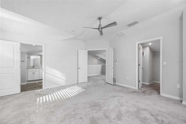 unfurnished bedroom featuring visible vents, a walk in closet, baseboards, and carpet floors