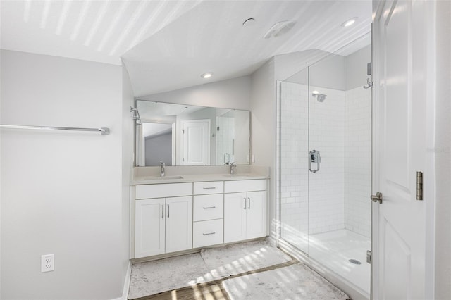 bathroom featuring double vanity, vaulted ceiling, a shower stall, and a sink