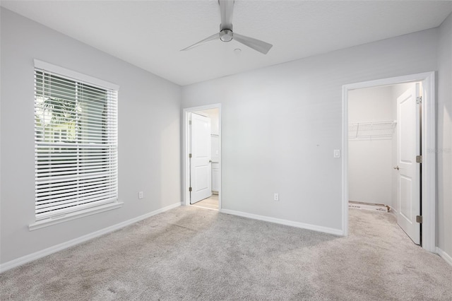 unfurnished bedroom with baseboards, a spacious closet, a closet, light colored carpet, and connected bathroom