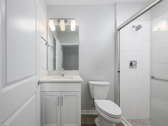 bathroom with vanity, toilet, baseboards, and a stall shower