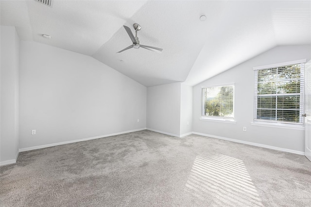 carpeted empty room featuring vaulted ceiling, a ceiling fan, baseboards, and a textured ceiling