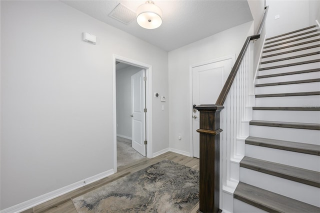 stairway with visible vents, baseboards, and wood finished floors