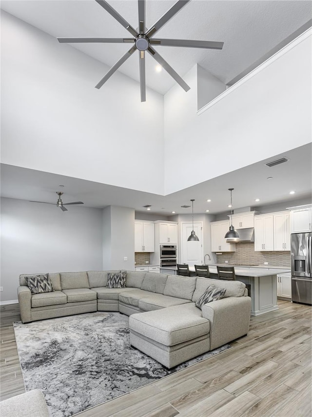 living room with visible vents, a ceiling fan, recessed lighting, light wood-style floors, and baseboards