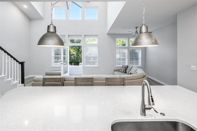 kitchen with open floor plan, pendant lighting, baseboards, and a sink