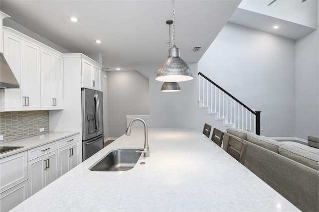 kitchen featuring tasteful backsplash, visible vents, stainless steel refrigerator with ice dispenser, white cabinetry, and a sink