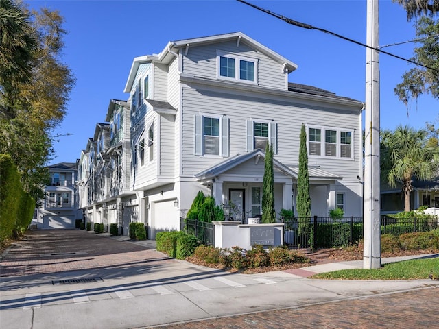 view of front facade featuring a fenced front yard, decorative driveway, a garage, and a residential view