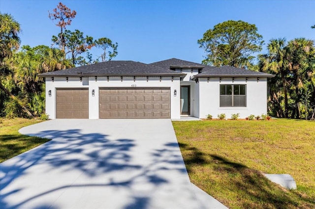 prairie-style home featuring stucco siding, driveway, a front yard, and a garage