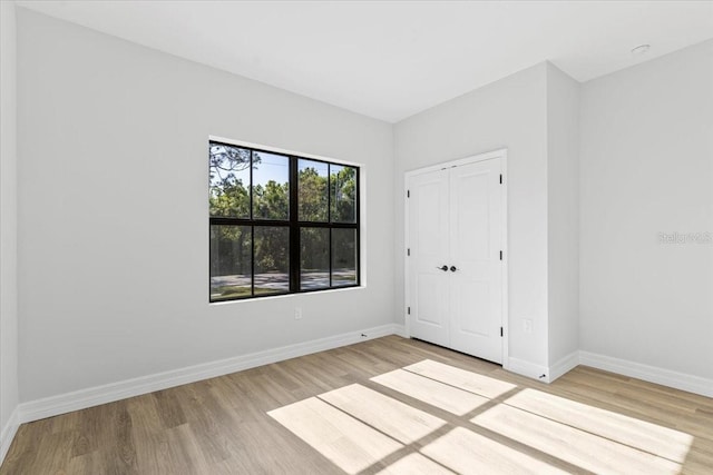 unfurnished bedroom with light wood finished floors, a closet, and baseboards