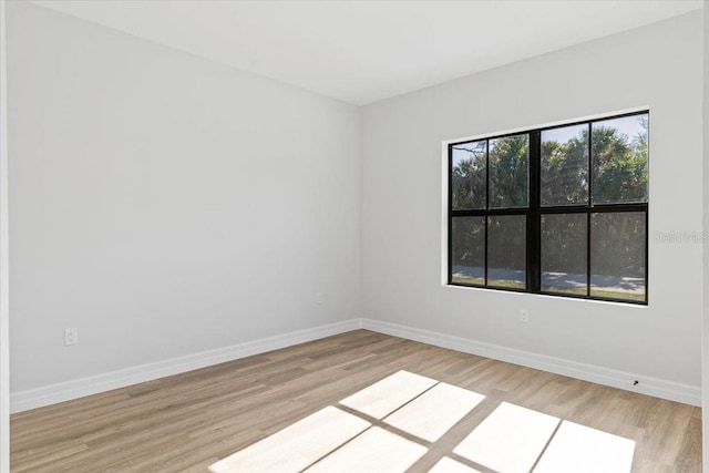 spare room featuring baseboards and wood finished floors