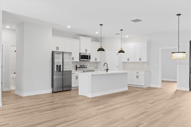 kitchen with light wood-style flooring, appliances with stainless steel finishes, white cabinets, and light countertops