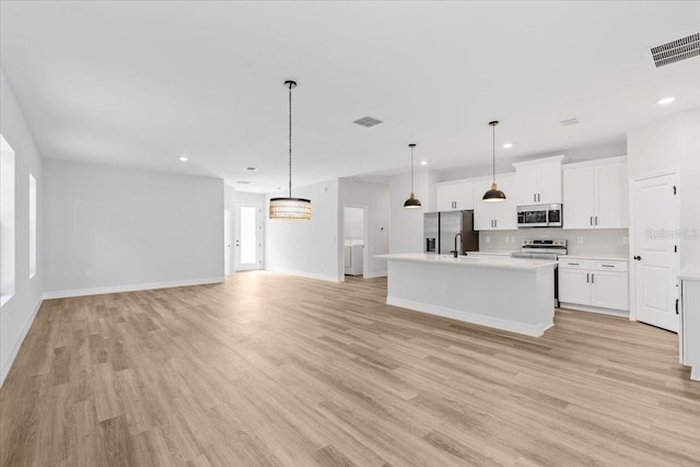 kitchen featuring visible vents, open floor plan, light countertops, light wood-type flooring, and stainless steel appliances