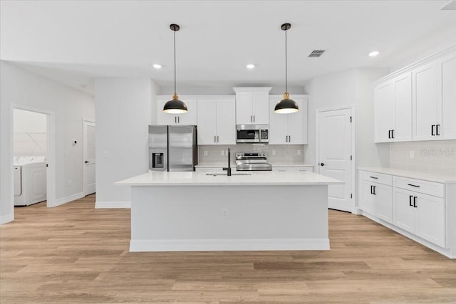 kitchen with light wood finished floors, visible vents, washer and dryer, and appliances with stainless steel finishes