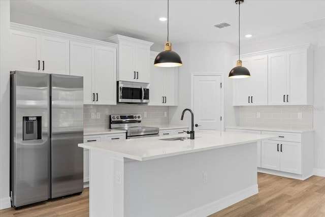 kitchen with white cabinets, appliances with stainless steel finishes, light wood-type flooring, and a sink