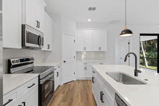 kitchen featuring a sink, light wood-style flooring, appliances with stainless steel finishes, and white cabinets