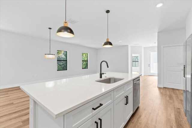 kitchen featuring pendant lighting, light wood-style floors, and a sink